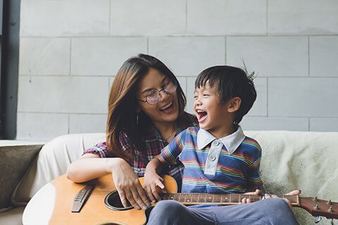 Woman in glasses playing guitar with son